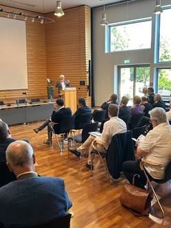 Viele Teilnehmende sitzen in der Aula und lauschen dem Referenten am Rednerpult.